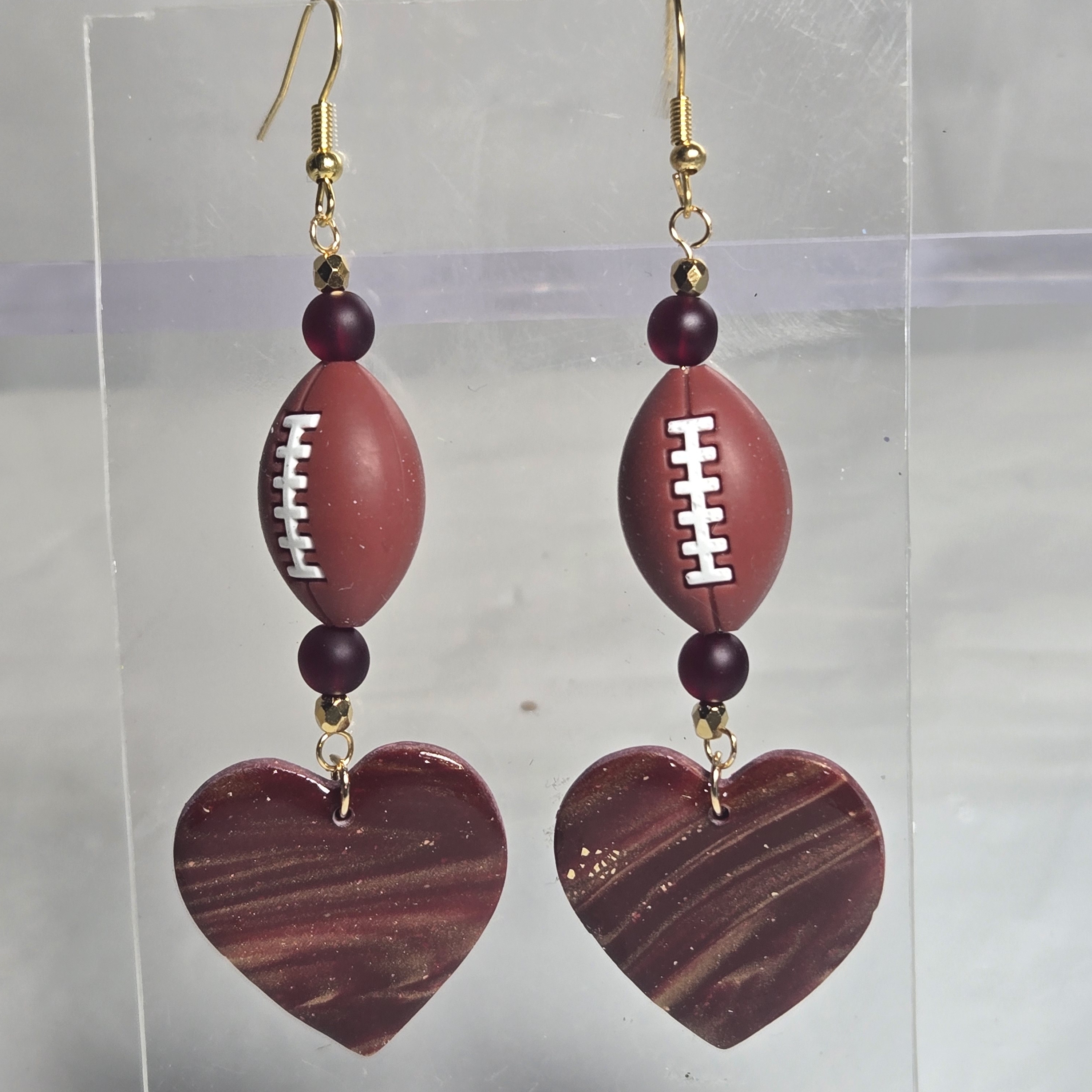 B224- Burgundy And Gold Heart And Football Dangle Earrings 20$